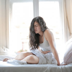 young woman in bed clutching her abdomen