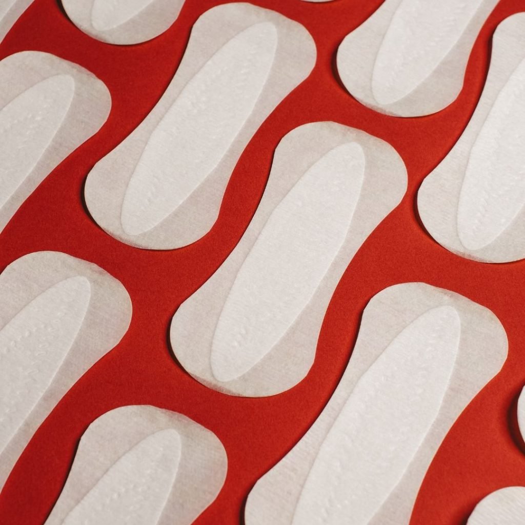 red background with rows of white period pads laid out