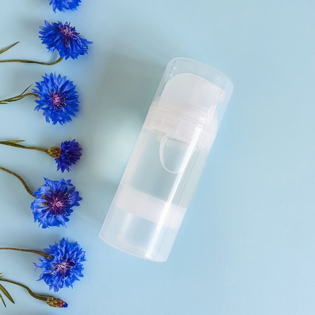 blue background with daisies along the left border and a clear plastic pump bottle filled with clear liquid in the centre