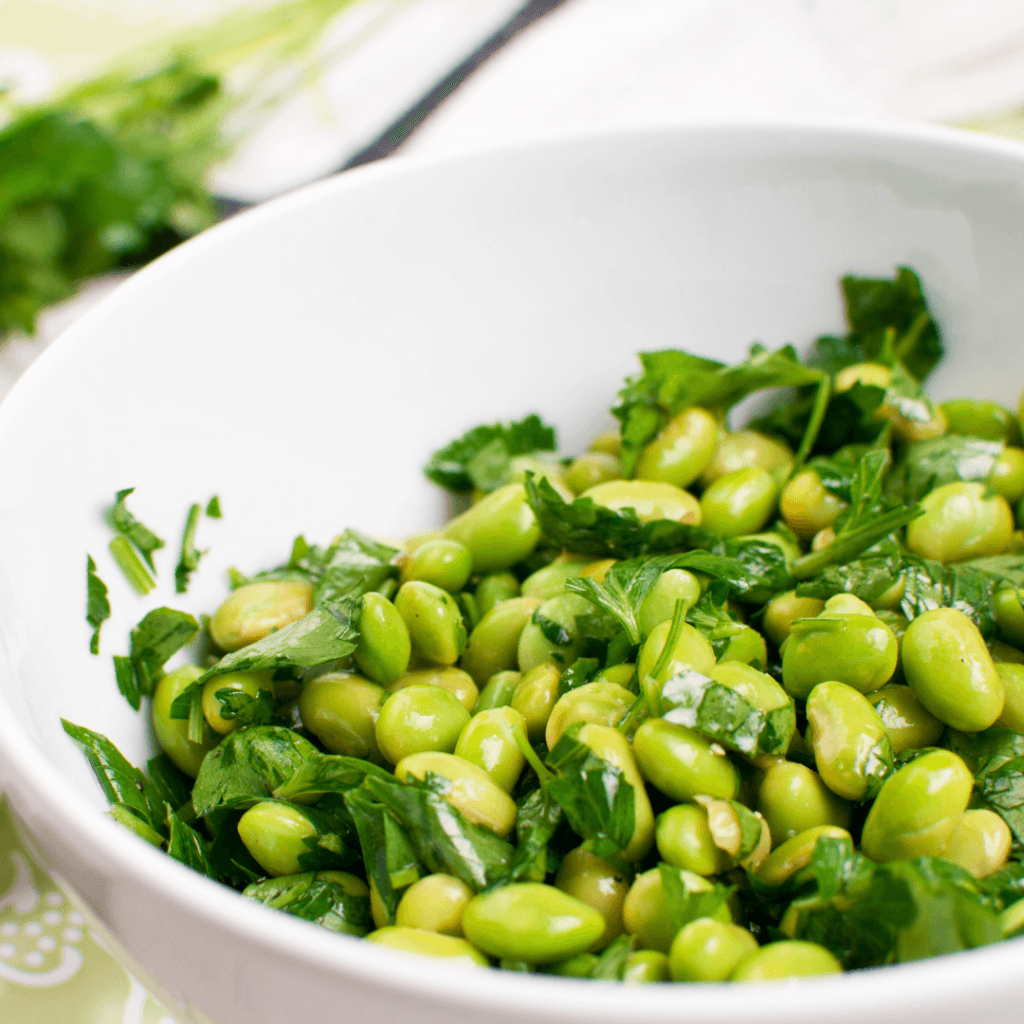 shelled edamame in a bowl with greens